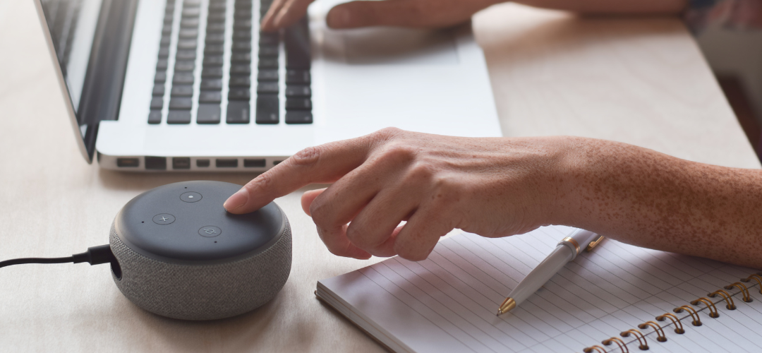 Hand pressing a button on a smart speaker